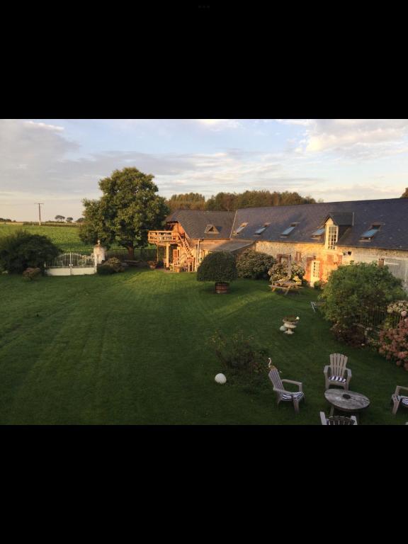 une grande cour avec des chaises et une maison dans l'établissement La Campagne à la Mer, proche d'Etretat, à Angerville-la-Martel