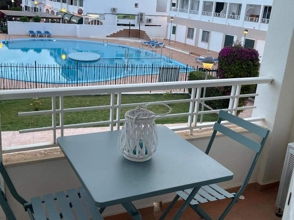 una mesa azul y sillas en un balcón con piscina en Calan Blanes con piscina, en Ciutadella