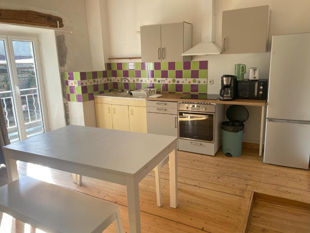 een keuken met een tafel, een fornuis en een koelkast bij Appartements de la ferme du Brocey in Crolles