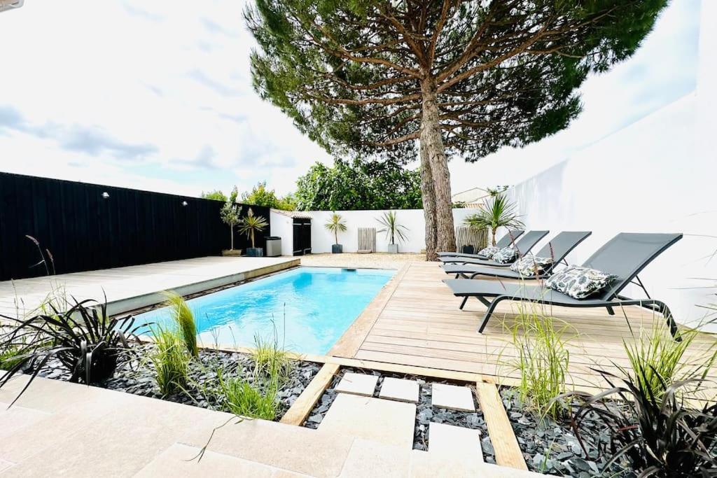 einen Hinterhof mit einem Pool und einer Terrasse mit Stühlen und einem Baum in der Unterkunft La Villa des Matelots in La Flotte