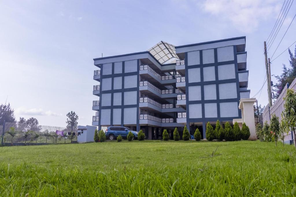 a building with a green field in front of it at The pine 1 bedroom house California plaza in Nanyuki