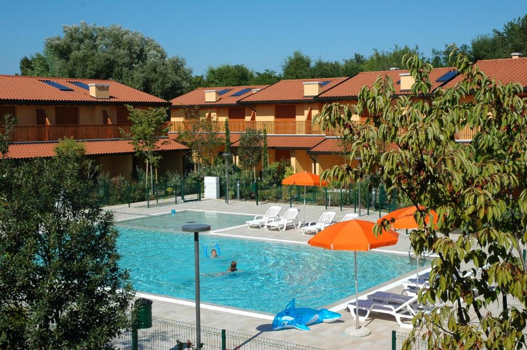 una piscina con sillas y sombrillas en un hotel en Villaggio Tamerici, en Lignano Sabbiadoro
