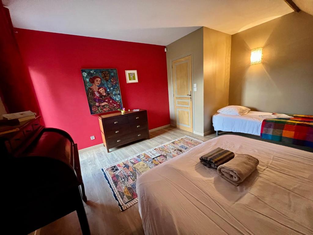 une chambre avec deux lits et un mur rouge dans l'établissement Villa de Simona, à Yvré-lʼÉvêque