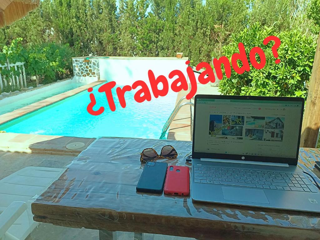 a laptop computer sitting on a table next to a pool at Casa en el campo con piscina en Murcia a 50 kilometros de las playas in La Ñora