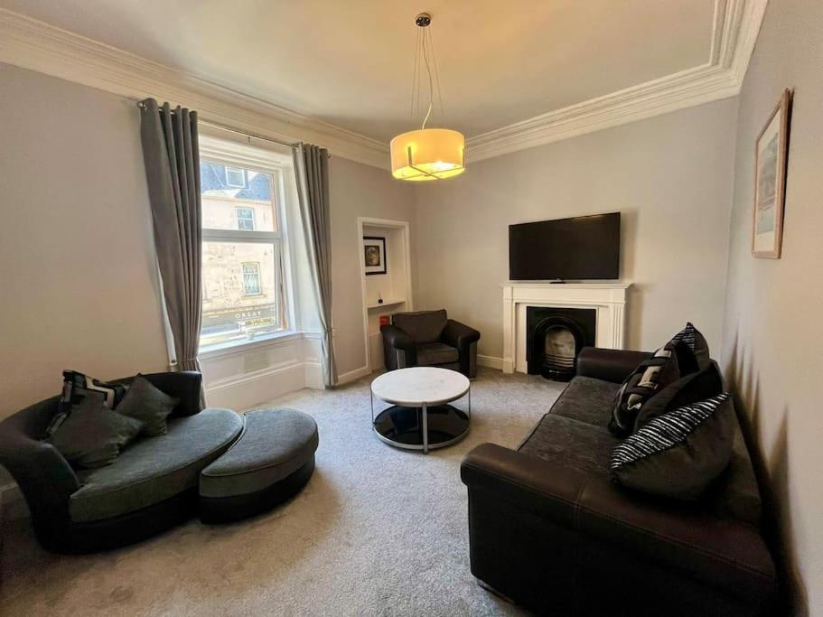 a living room with a couch and chairs and a fireplace at Beautiful spacious apartment in town centre in Oban