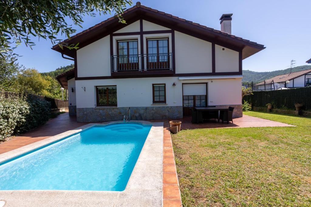 a villa with a swimming pool in front of a house at URDAIBAI Boutique in Altamira