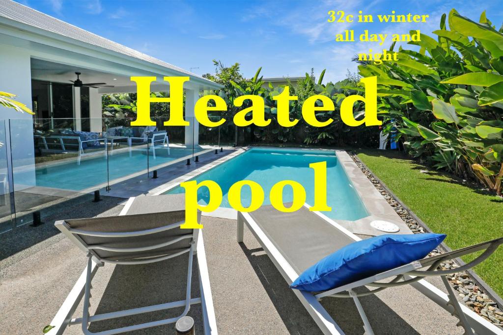 パーム・コーブにあるSeaside 300m to beach 32c pool for cooler monthsの椅子と温水プールを備えたスクリーン付きプール