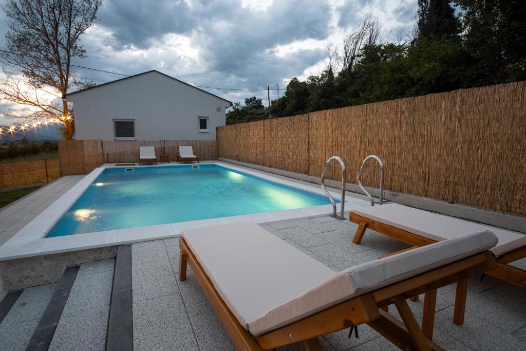 a swimming pool with two chairs and a fence at Natura Apartmani in Ljubuški