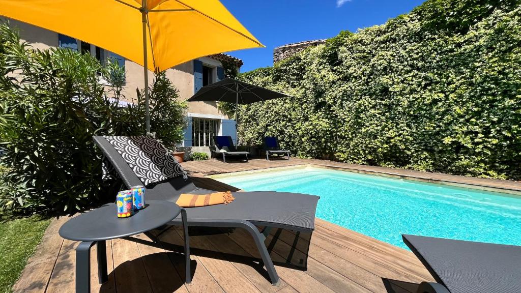 a chair and an umbrella next to a swimming pool at Chambres B&B dans Authentique Mas de Village avec Piscine in Robion en Luberon