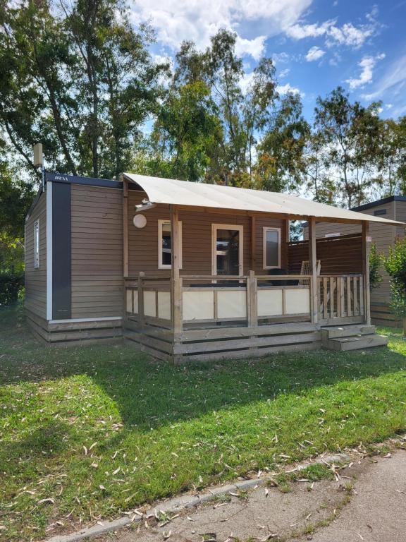 une petite maison avec une terrasse couverte sur une cour dans l'établissement Mobil home 4 personnes climatisé, à Hyères