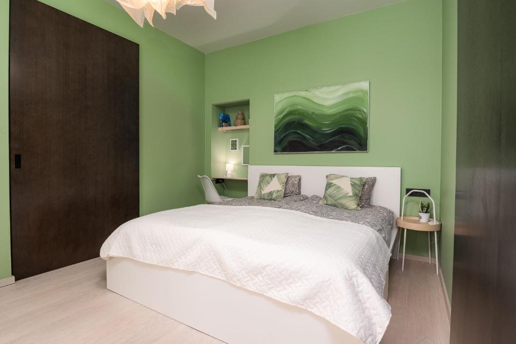 une chambre avec un grand lit aux murs verts dans l'établissement Spacious and Modern City Centre Deluxe Entire Flat for business and holiday, à Pärnu