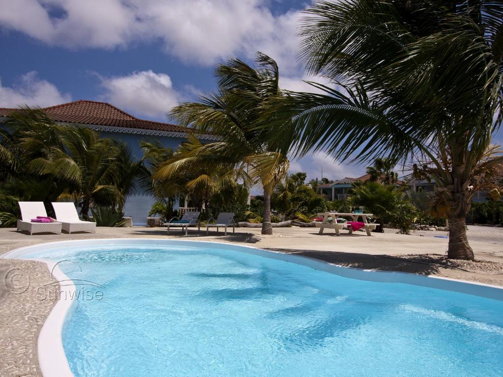 una piscina con palmeras en un complejo en Tortuga, en Kralendijk