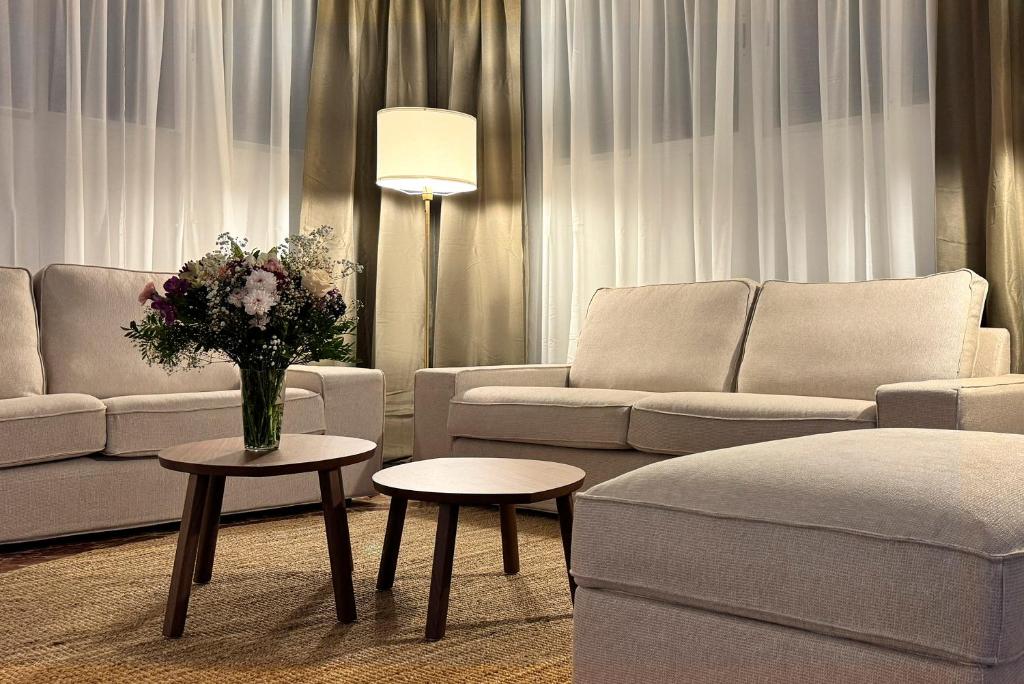 a living room with couches and tables with flowers at Hotel Don Ignacio in San José