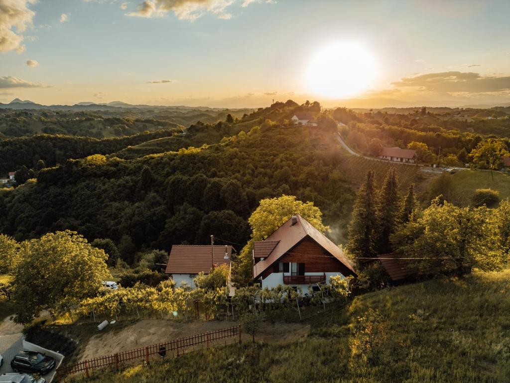 una casa en una colina con la puesta de sol en el fondo en Cozy family place 'Hiša Grozdek' - Gruškovec 40A en Gruškovec