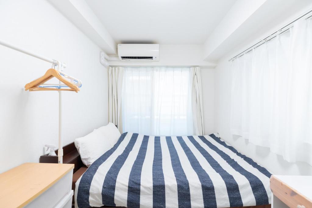 1 dormitorio con cama de rayas y ventana en The Emilio 102 Shinjuku newly renovated and opened in June 2024, en Tokio
