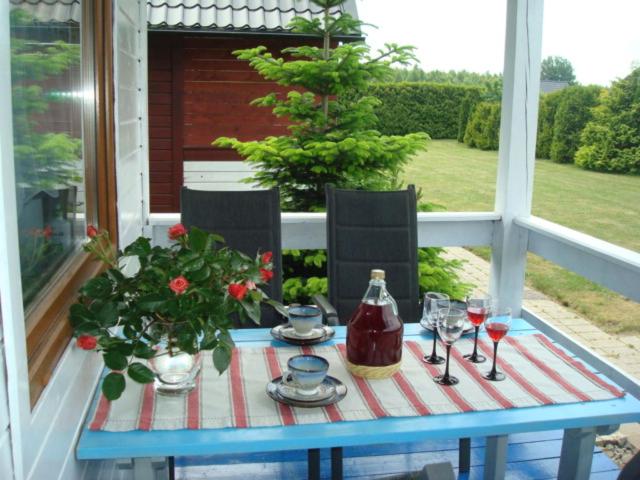 a table with wine glasses and a bottle on a porch at Domki Małgorzata in Władysławowo