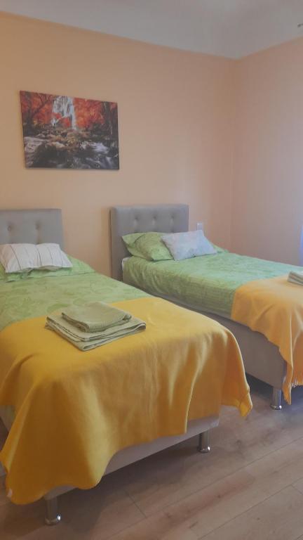 2 camas en una habitación con sábanas amarillas. en Szahara Vendégház en Kerekegyháza