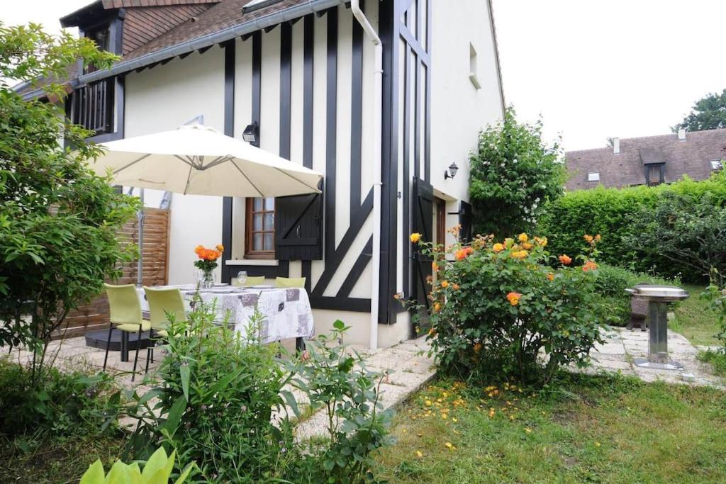 - une table avec un parasol à côté d'une maison dans l'établissement Maison mer jardin 4 personnes, à Houlgate