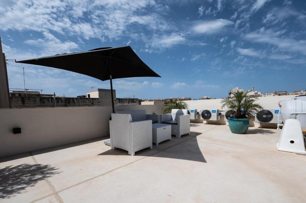 a patio with chairs and an umbrella on a roof at Dar Barbara- Studio Apartments with Roof terrace in Cospicua