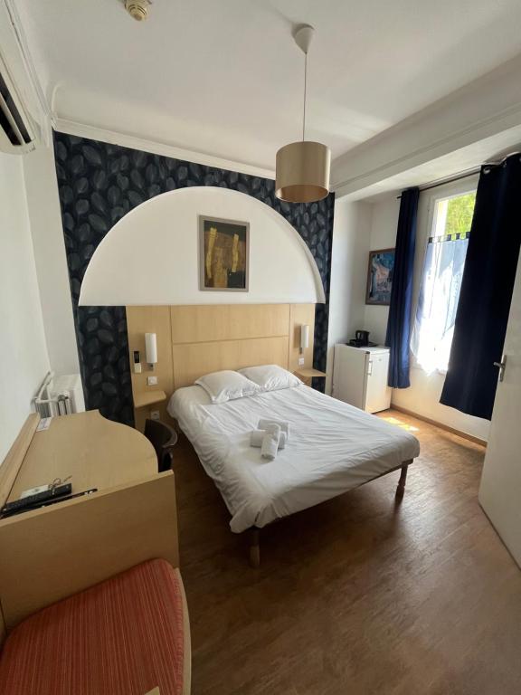 una camera con letto e scrivania di Hôtel Trianon a Juan-les-Pins