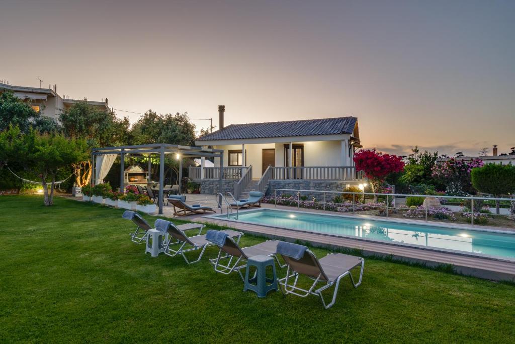 a backyard with a swimming pool with chairs and a house at Santy Villa in Gerani Chanion