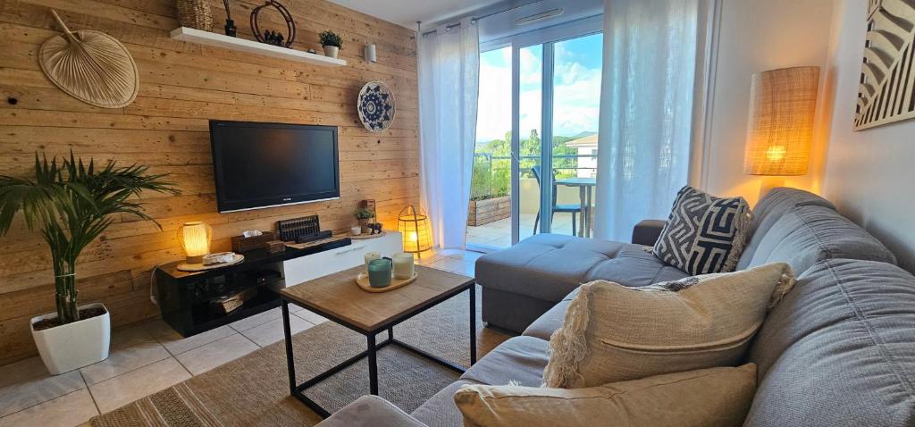 a living room with a couch and a tv at Appartement 2 pièces Cosy au calme climatisé 3 étoiles in Fréjus