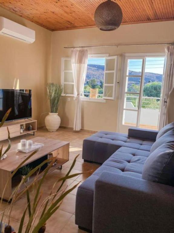 a living room with a blue couch and a table at Olives Villa in Sinoikismós Kámbos