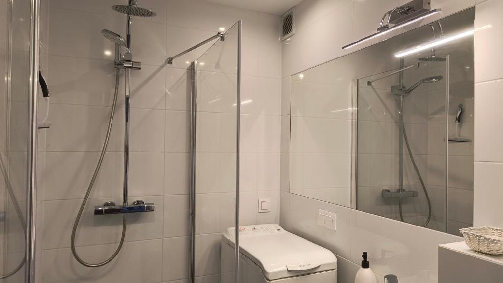 a white bathroom with a shower and a toilet at Mieszkanie w Gdańsku in Gdańsk