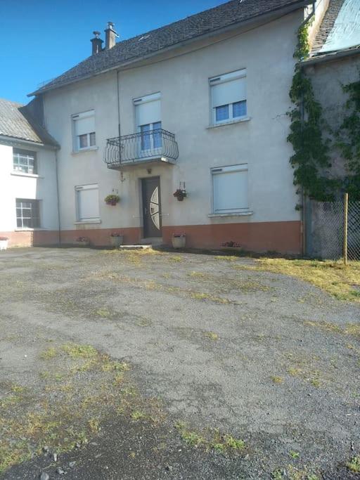 Cette grande maison blanche dispose d'un balcon et d'une allée. dans l'établissement Gîte de vacances 12 couchages plus 2 lits bébés, à La Chaze-de-Peyre