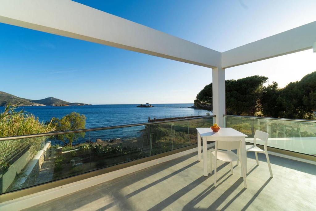 una mesa blanca y sillas en un balcón con vistas al océano en Villa Agios Isidoros, en Gourna