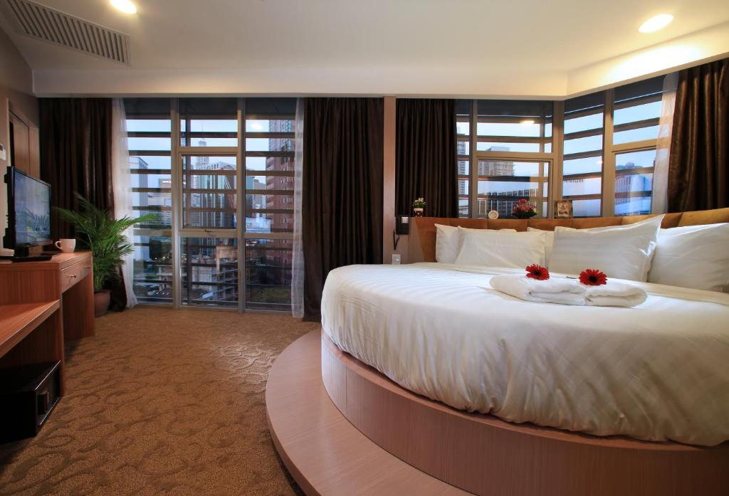 um quarto com uma cama grande com duas flores em Izumi Hotel Bukit Bintang Kuala Lumpur em Kuala Lumpur