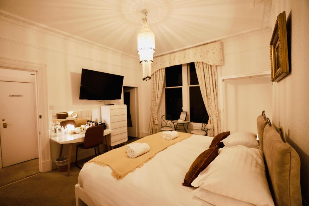 Dormitorio con cama, escritorio y TV en Doune Guest House, en St Andrews