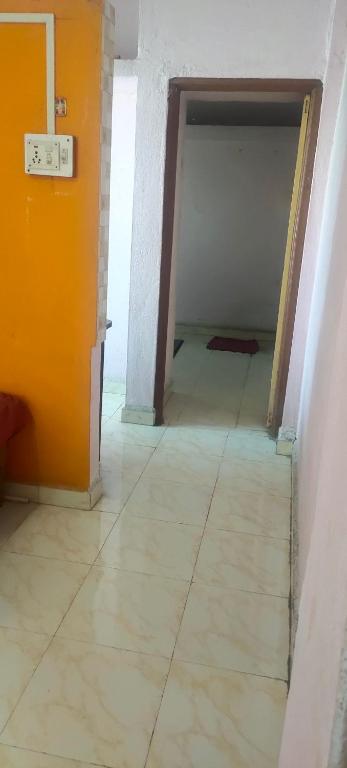 pusty pokój z pomarańczową ścianą i podłogą wyłożoną kafelkami w obiekcie Radhesham bhakt niwas w mieście Pandharpur