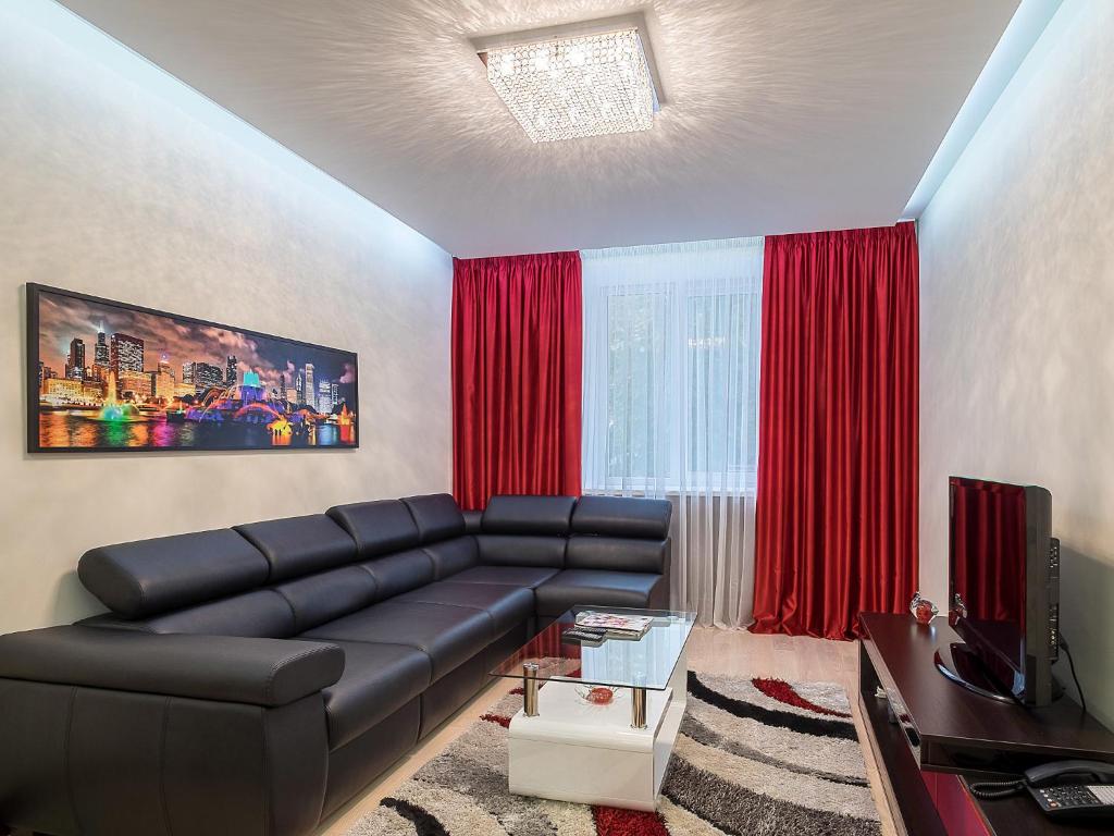 a living room with a black leather couch and red curtains at Center Apartment in Minsk
