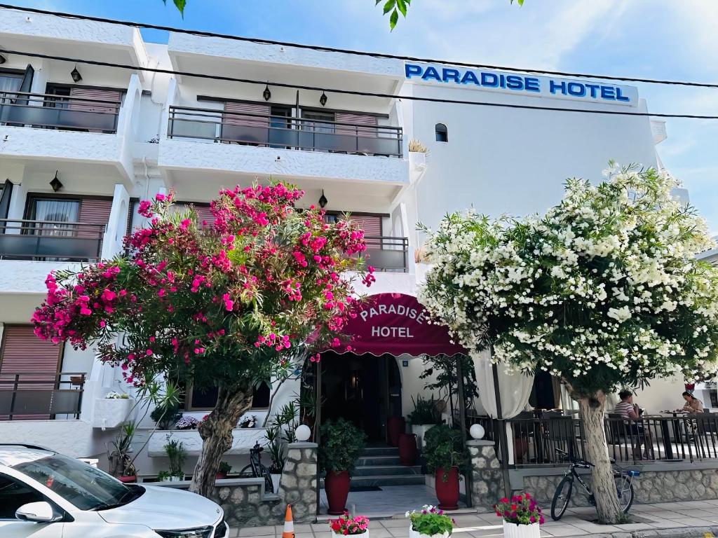a hotel with flowering trees in front of it at Paradise Hotel in Kos Town