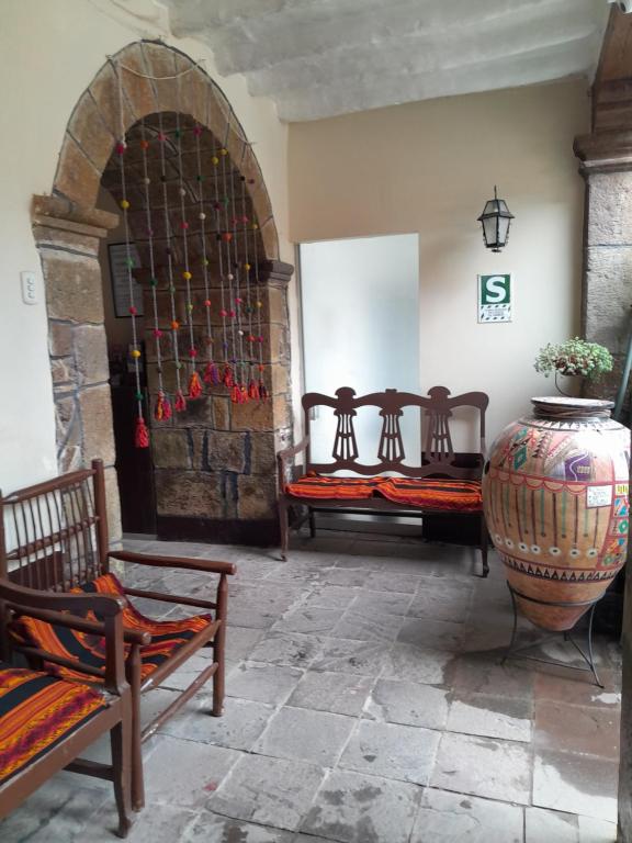 una habitación con 3 bancos y un jarrón grande en Puma walkers, en Cusco