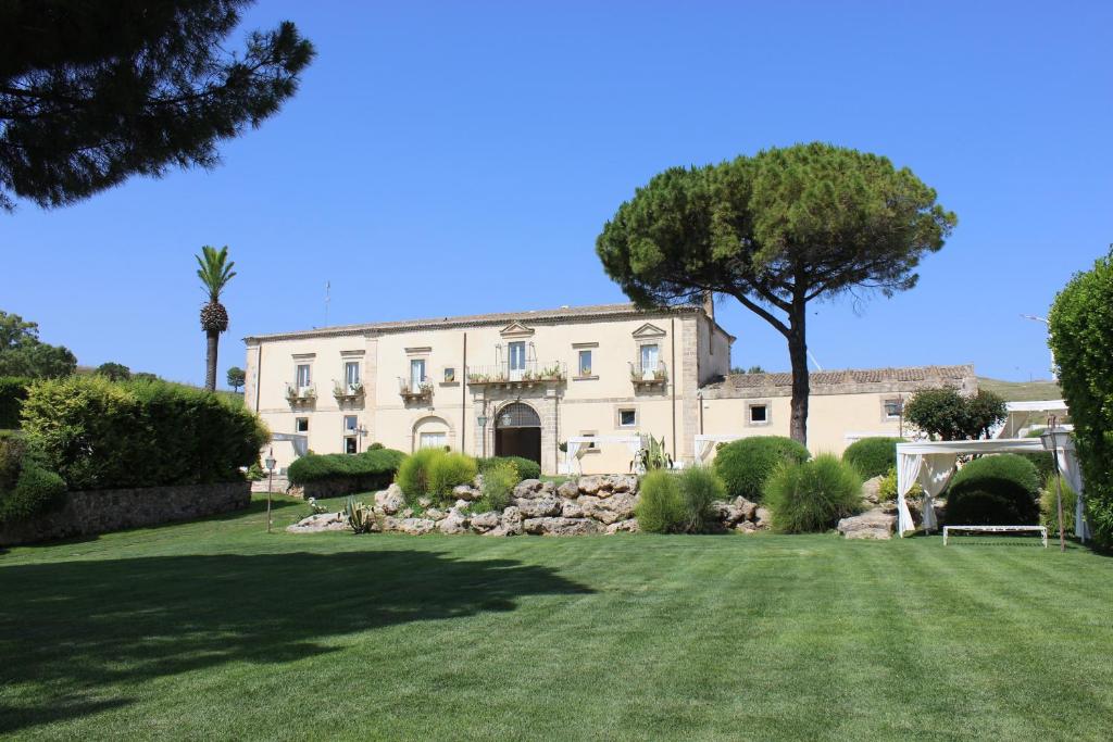 Vizzini的住宿－卡斯特羅卡米尼旅館，一座白色的大建筑,院子中有一棵树