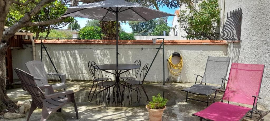 un patio avec une table, des chaises et un parasol dans l'établissement Charmant appartement de vacances, à Argelès-sur-Mer