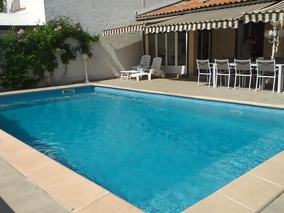 - une piscine bleue avec des chaises et une table dans l'établissement villa spacieuse avec piscine, à La Crau