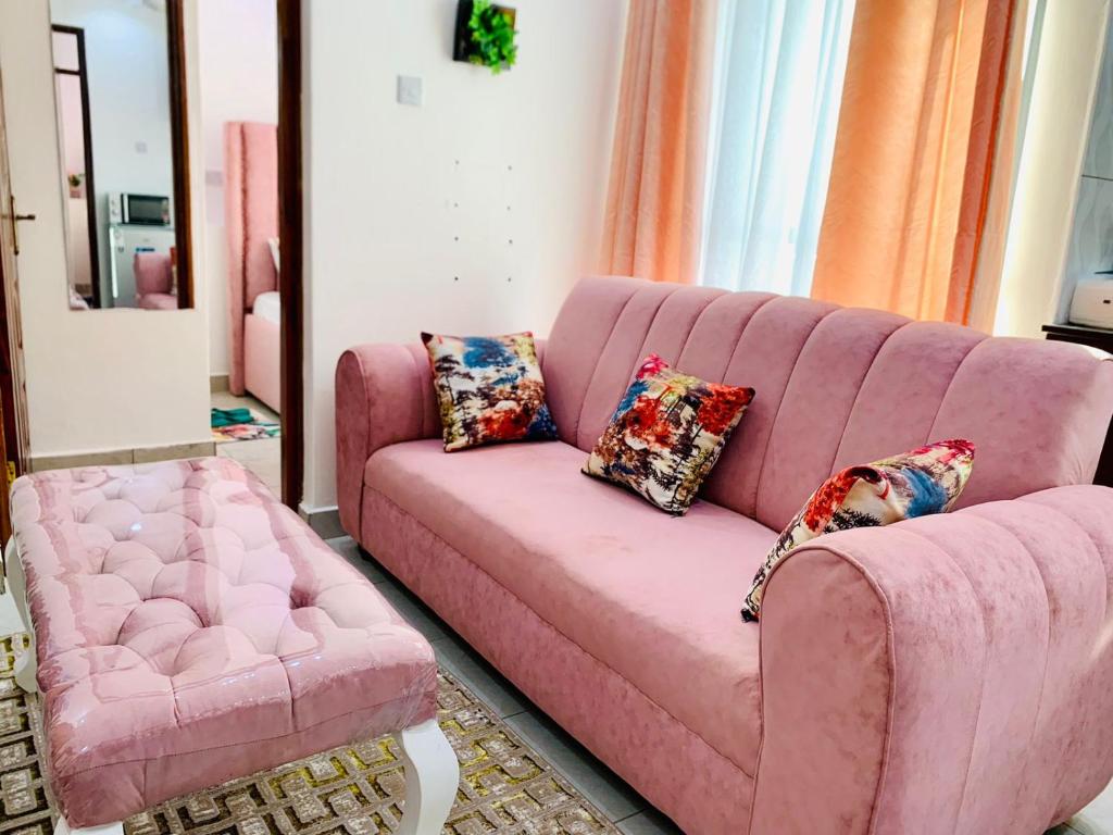 a pink couch and a chair in a living room at Khalisee homes 2 bedroom apartment in Bamburi in Mombasa