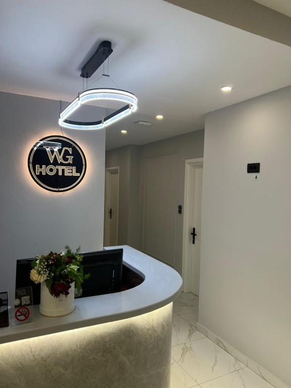 a lobby with a reception desk and a sign on the wall at WG Hotel in Ksamil