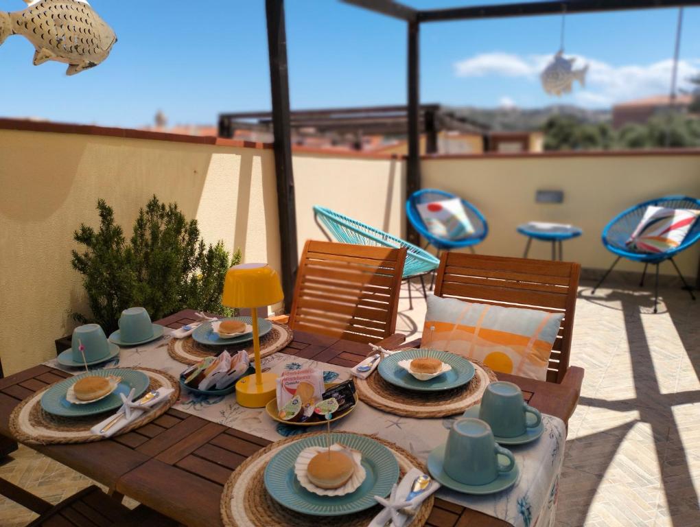 un tavolo in legno con piatti di cibo su un patio di Appartamento La Terrazza - Località Cala Gavetta a La Maddalena