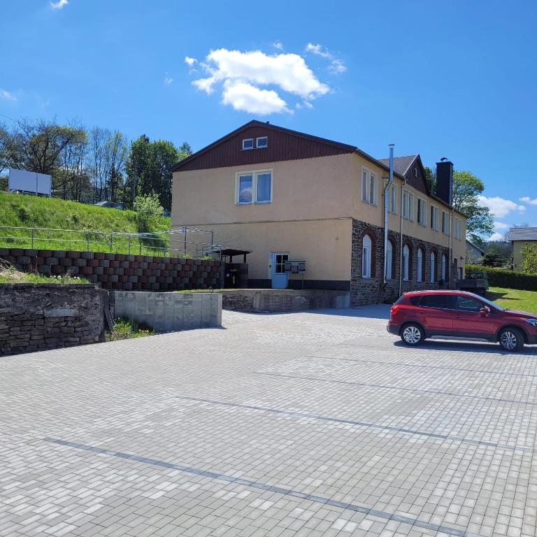 ein rotes Auto, das vor einem Haus parkt in der Unterkunft Ferienwohnungen An der Fichtelbergbahn in Cranzahl