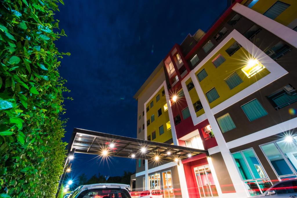 a parking lot in front of a building at night at Trendy Hotel in Nakhon Pathom