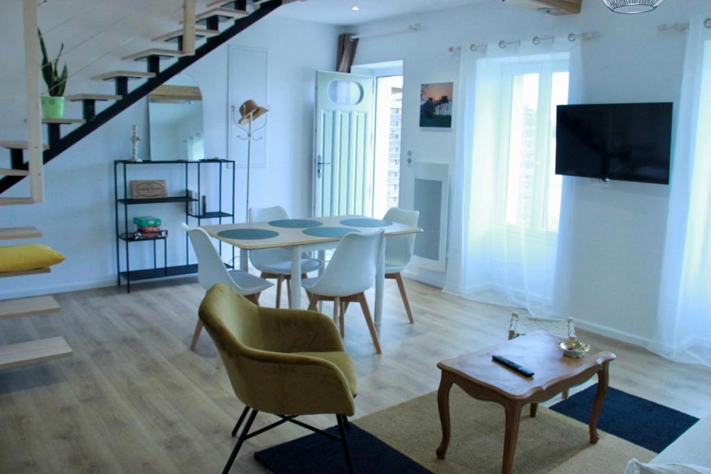a living room with a dining room table and chairs at Le figuier in Saint-Sauveur