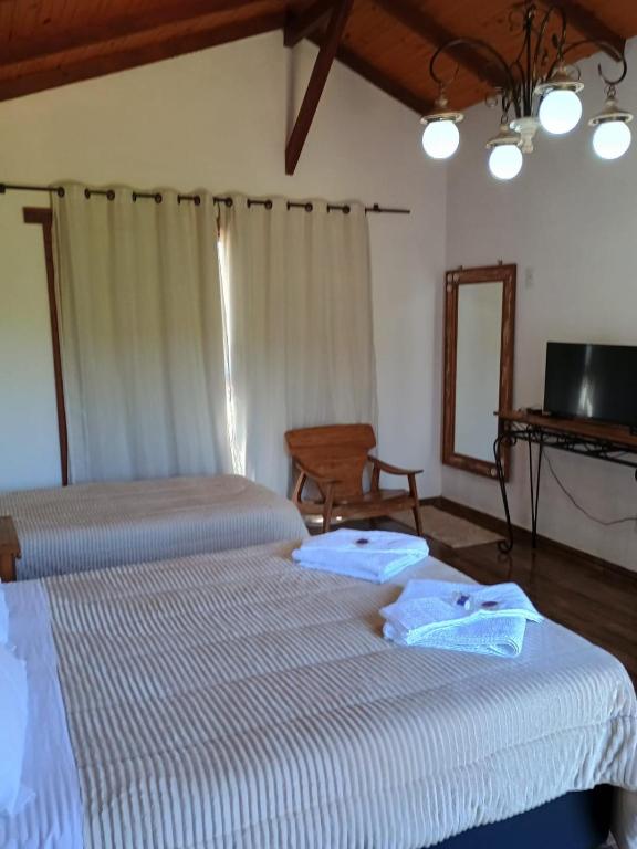 um quarto com 2 camas, um espelho e uma televisão em Chalé Torneados em Tiradentes