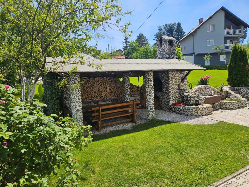 a wooden bench sitting under a pavilion in a yard at Apartman Rakovica in Sarajevo