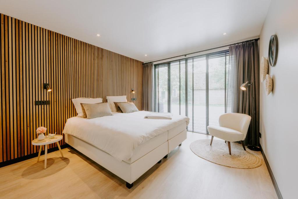 Un dormitorio con una gran cama blanca y una silla. en Bed & Breakfast BBNo9, en Arum