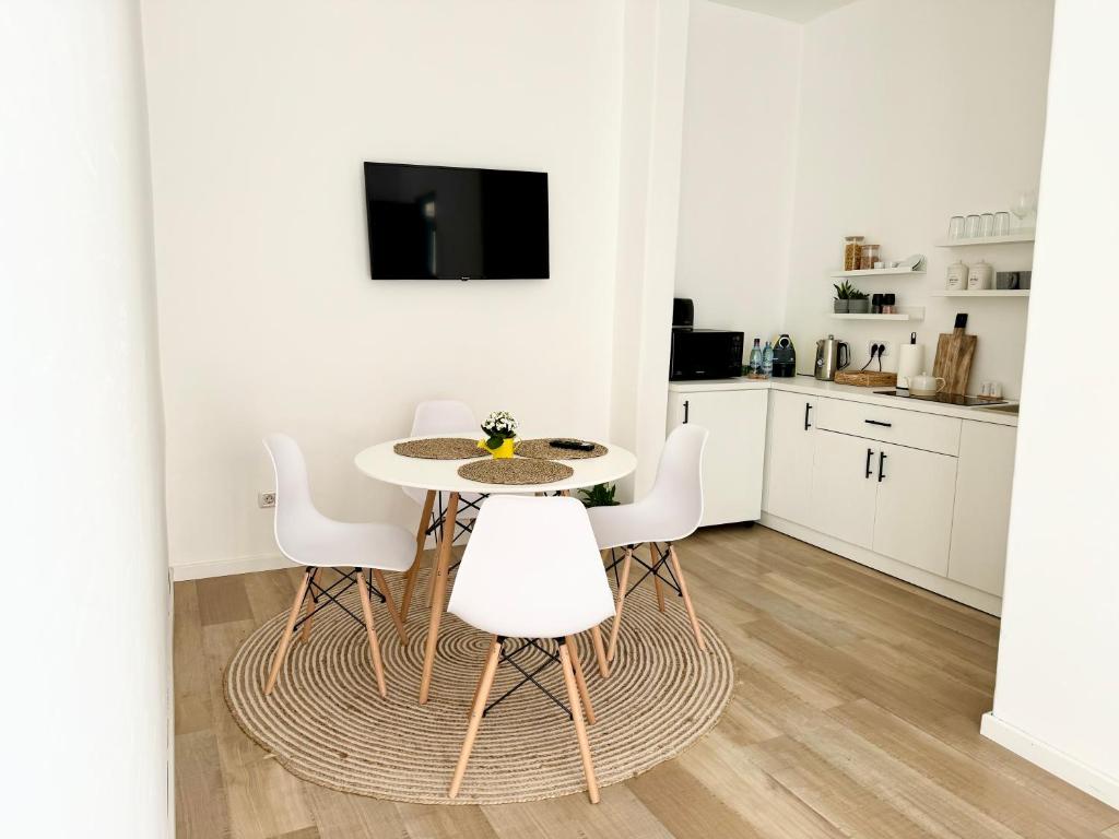 Biała kuchnia ze stołem i białymi krzesłami w obiekcie A.I. Apartment Arad w mieście Arad