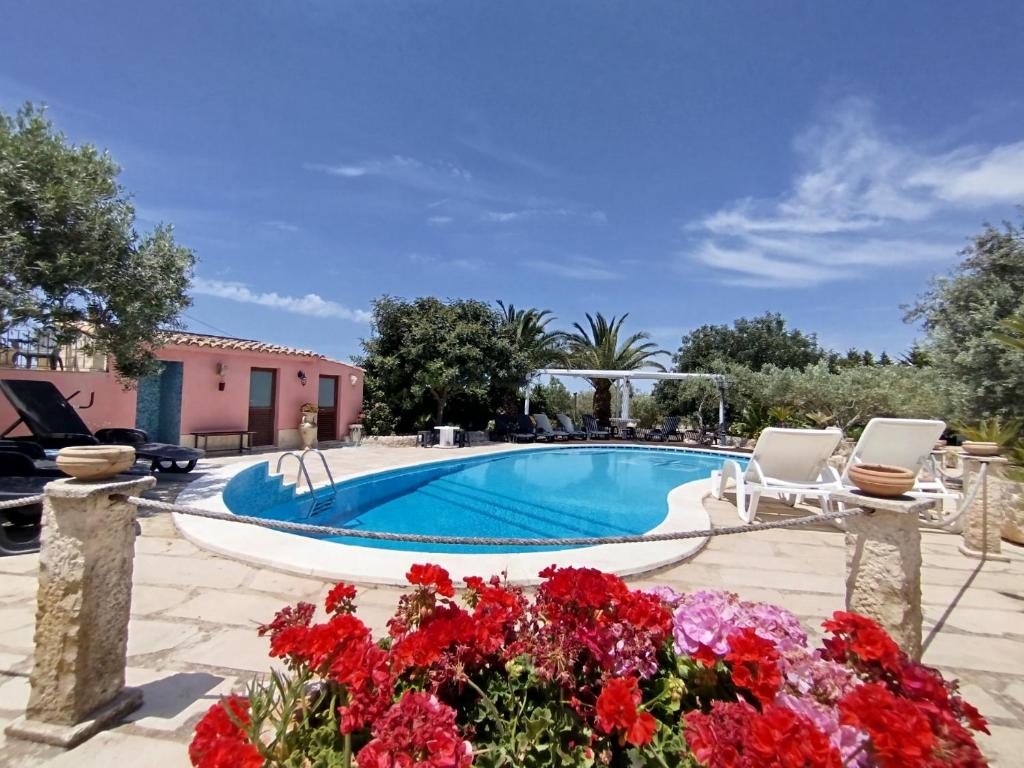 einen Pool mit zwei Stühlen und Blumen in der Unterkunft Villa Vi in Ragusa